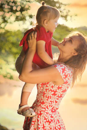 Mom with a baby on the river bankの写真素材