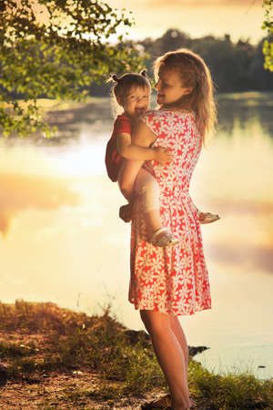 Mom with a baby on the river bankの写真素材