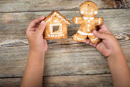 Baby hands holding a Christmas cookie on a wooden table