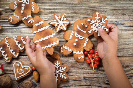Baby hands holding a Christmas cookie on a wooden table