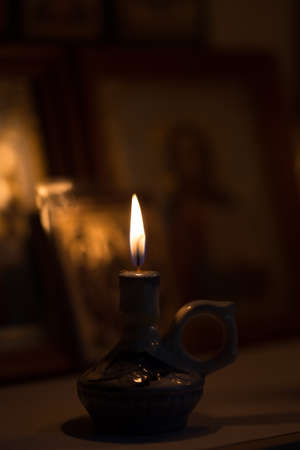 A burning candle against the background of orthodox icons in a dark roomの写真素材