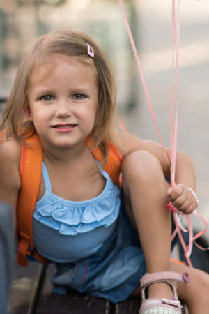 A girl of three years is sitting on a bench with balloonsの写真素材