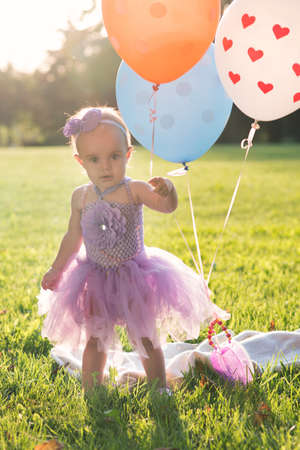 A little girl of fourteen months old is sitting on the grassの写真素材