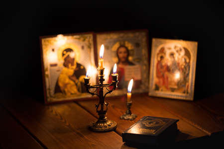 A burning candle against the background of orthodox icons in a dark roomの写真素材