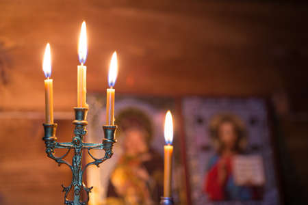 A burning candle against the background of orthodox icons in a dark roomの写真素材