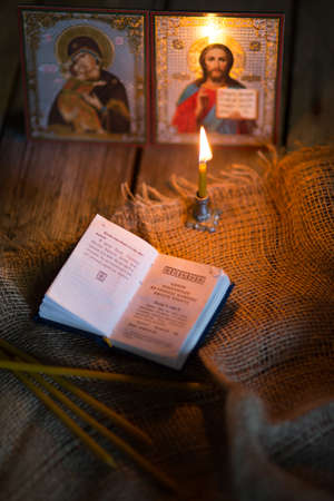 A burning candle against the background of orthodox icons in a dark roomの写真素材