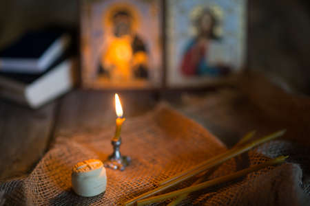 A burning candle against the background of orthodox icons in a dark roomの写真素材