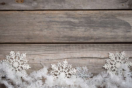 white tinsel and snowflakes on an old wooden boardの写真素材