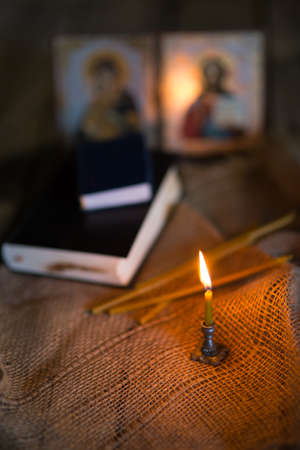 A burning candle against the background of orthodox icons in a dark roomの写真素材
