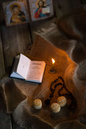 A burning candle against the background of orthodox icons in a dark roomの写真素材