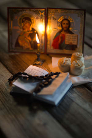 A burning candle against the background of orthodox icons in a dark roomの写真素材