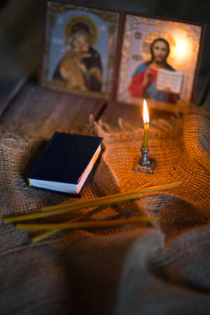 A burning candle against the background of orthodox icons in a dark roomの写真素材