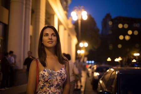 Beautiful young woman is walking in the night city.の写真素材