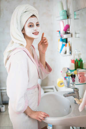 Young woman looks after the face makes a mask  in the bathroomの写真素材