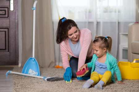Mom and daughter are cleaning in the apartment, a woman and a girl of three years doing household choresの写真素材