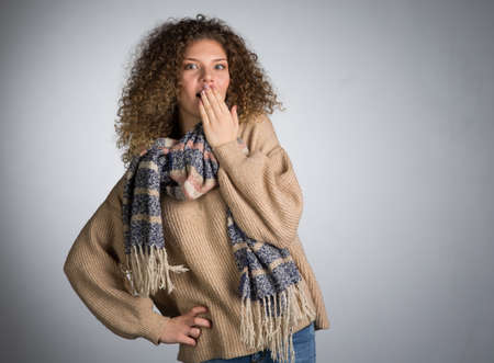 Young woman with curly hair, studio, A woman in a scarf covered her mouth with surpriseの写真素材