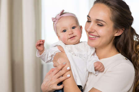 A young mother plays with a baby. A woman plays with a baby eight months of age