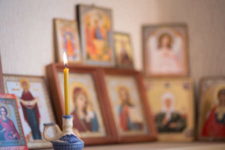 A burning candle against the background of orthodox iconsの写真素材