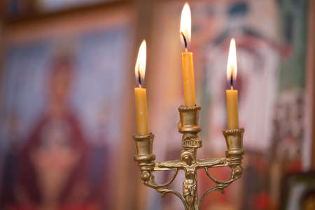A burning candle against the background of orthodox iconsの写真素材