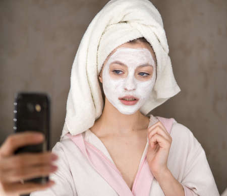 Young woman looks after the face makes a mask in the bathroom