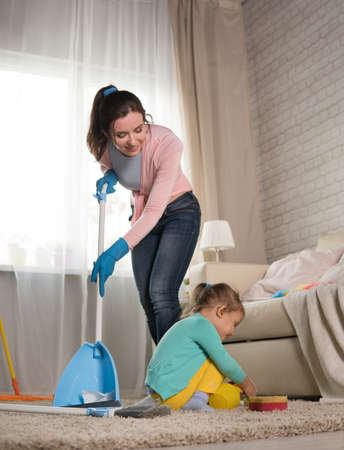 Mom and daughter are cleaning in the apartment, a woman and a girl of three years doing household...