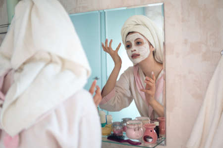 Young woman looks after the face makes a mask in the bathroomの写真素材