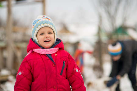Children mold Snowman with a carrot in the yard winter, Boy and girl play with snowの写真素材