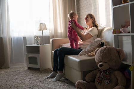 A young mother plays with a baby. A woman plays with a baby eight months of ageの写真素材