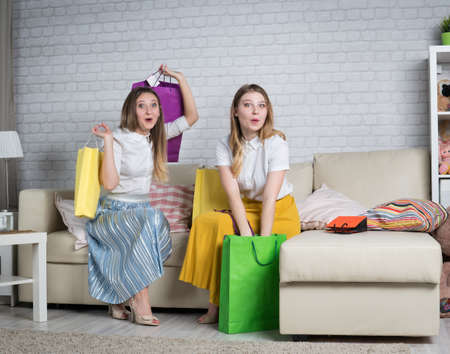 Two young women dismantle packages with shopping at home