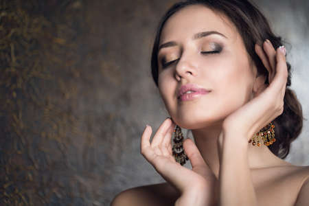 Young beautiful elegant woman in evening gold dress with beautiful hairdoの写真素材