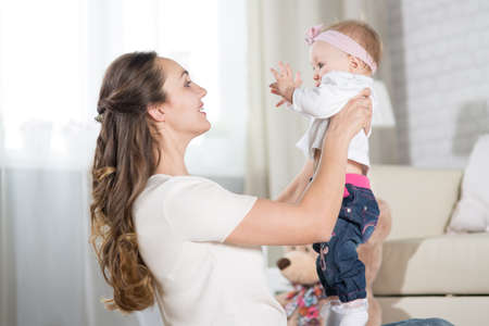 A young mother plays with a baby. A woman plays with a baby eight months of ageの写真素材