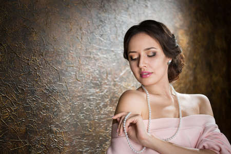 Young beautiful elegant woman in evening gold dress with beautiful hairdo の写真素材