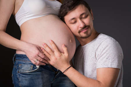 Husband and pregnant wife on gray background, happy couple の写真素材