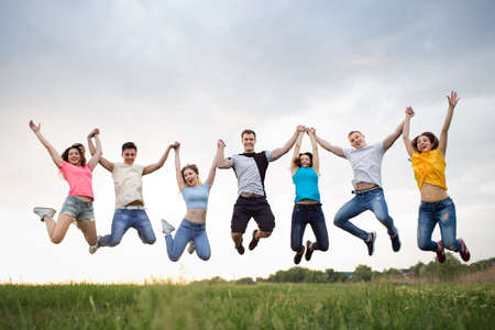Young people jumping against the beautiful sunset sky