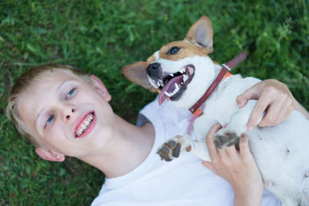 A teenager with a dog in the nature, Jack Russell and a boy playing
