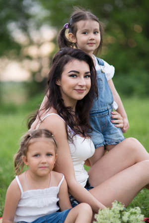 Mom and daughter on the grass in the park, a woman and children in natureの写真素材
