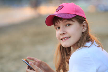 A girl of thirteen years near the sea, with a phone in her hands