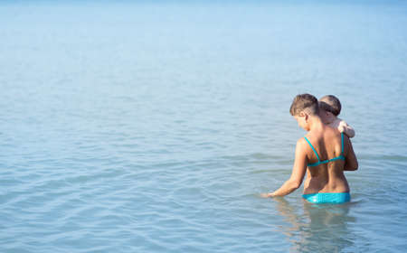Mom with a baby on the sea, a woman with a child rides on the sea for one yearの写真素材