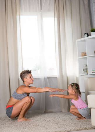 mom and daughter doing exercises together in the roomの写真素材