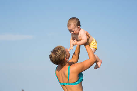 Mom with a baby on the sea, a woman with a child rides on the sea for one yearの写真素材