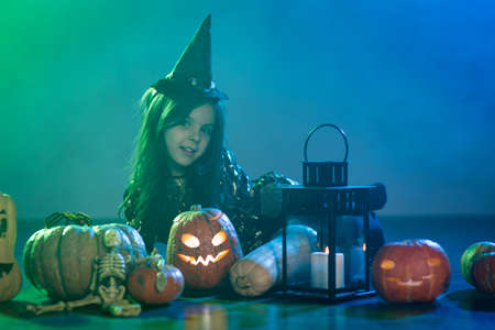 Baby girl in a witch costume for Halloween with a pumpkin
