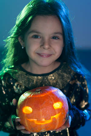 Baby girl in a witch costume for Halloween with a pumpkin in his handsの写真素材