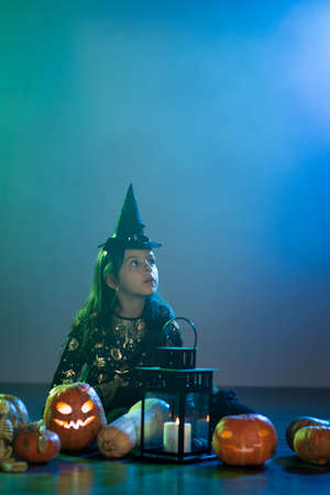 Baby girl in a witch costume for Halloween with a pumpkinの写真素材