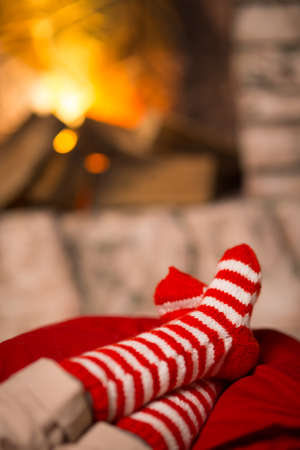 feet of the child in striped socks are heated near the fireplaceの写真素材