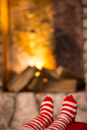 feet of the child in striped socks are heated near the fireplace
