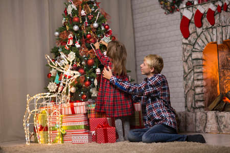 brother and sister near the Christmas tree on Christmas nightの写真素材