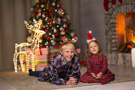 brother and sister near the Christmas tree on Christmas nightの写真素材