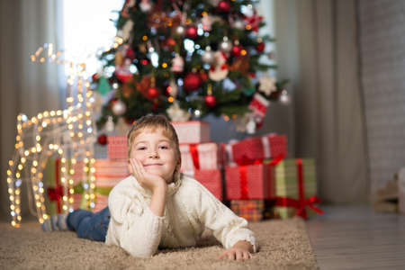 a boy of seven years old posing near the Christmas treeの写真素材