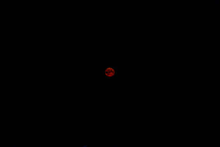A total red color super moon lunar eclipse isolated in the dark night sky. Unusual atmospheric...