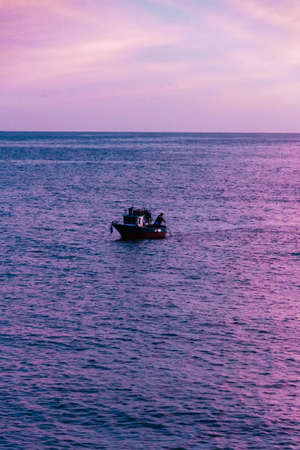 Gorgeous wallpaper sundown background at Amalfy coast, Italy with magnificent luminous colors and fishermen on a boat fishing. Beautiful sunset over the sea, holyday, vacation conceptのeditorial素材